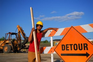 Construction worker standing by detour sign